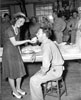 Young lady feeding a piece of cake to the chaplain during an organizational party.